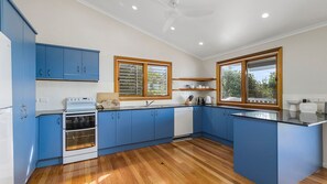 A modern kitchen with blue cabinets, a white stove, and a large window.