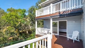 A two-story building with a balcony and a bedroom with a bed and a chair.
