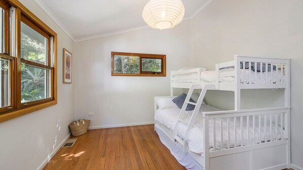 A room with bunk beds, a window with a view of trees, and a hanging light fixture.