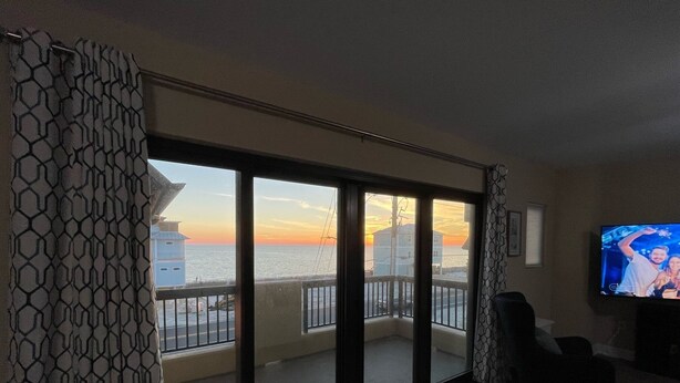 Una sala de estar con un amplio ventanal corredizo que da a un balcón con vista al mar.