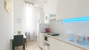 Eine moderne Küche mit weißen Schränken, einem eingebauten Backofen und blauer Beleuchtung unter den Schränken.