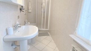 Ein Badezimmer mit einem weißen Waschbecken, einer Toilette und einer Dusche.