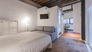 Un dormitorio con cama, televisor y vista al exterior.
