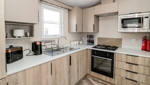 Una cocina moderna con horno empotrado, microondas y estufa a gas.