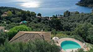 A villa with a swimming pool surrounded by lush greenery and a view of a large body of water. - Kerasia Bay View Villa (Corfu)