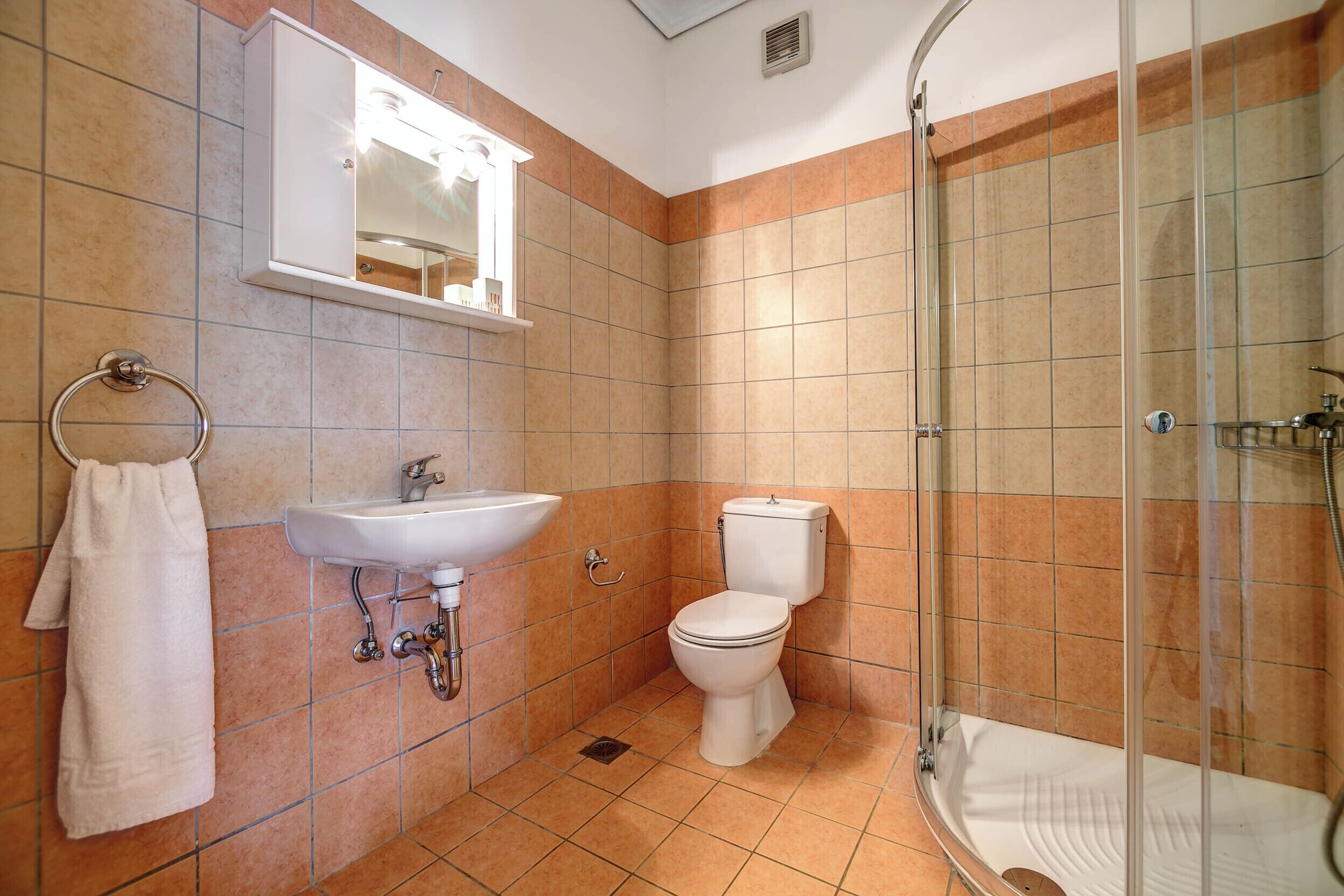 A bathroom with a sink, toilet, and glass-enclosed shower.