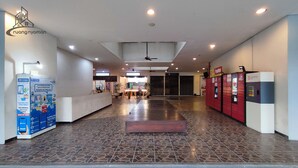 A spacious lobby with a central seating area, a reception desk, and a PopBox vending machine. - Apartmen Serpong GreenView byRuangNyaman (South Tangerang)