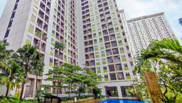 A high-rise residential building with multiple balconies, a swimming pool, and surrounding greenery. - Apartmen Serpong GreenView byRuangNyaman (South Tangerang)