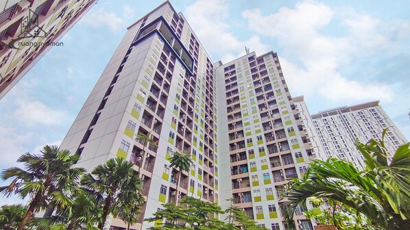 Edificio residencial alto con varios balcones, rodeado de palmeras.