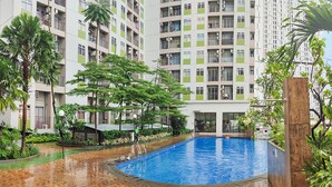 A residential building with a swimming pool surrounded by greenery. - Apartmen Serpong GreenView byRuangNyaman (South Tangerang)