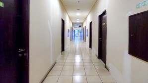A long, narrow hallway with doors on both sides, tiled floor, and overhead lighting. - Apartmen Serpong GreenView byRuangNyaman (South Tangerang)
