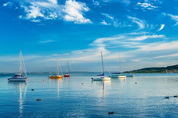 A calm harbor with several sailboats anchored in the water, surrounded by a clear sky. - Treasure Of The Past (Balatonrendes)