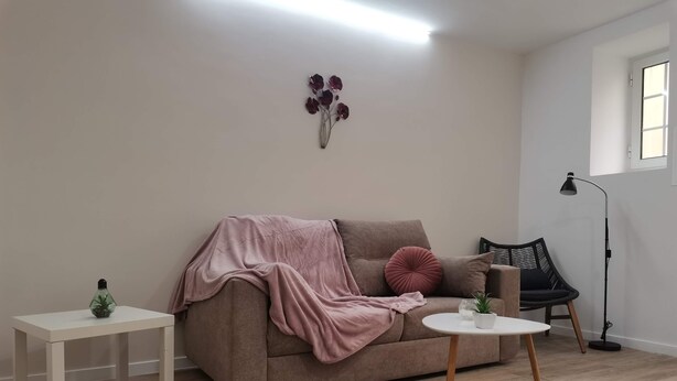A living room with a sofa, a small side table, a coffee table, a floor lamp, and a potted plant. - 1 bedroom apartment São Gião 10 in Tomar (Tomar)