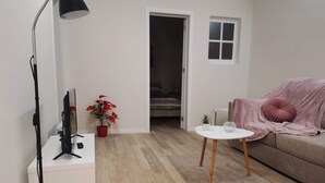 A modern living room with a white sofa, a small white table, a red potted plant, and a black floor lamp. - 1 bedroom apartment São Gião 10 in Tomar (Tomar)