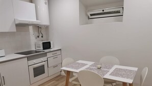 A compact kitchen with white cabinets, a microwave, and a small dining table with chairs. - 1 bedroom apartment São Gião 10 in Tomar (Tomar)