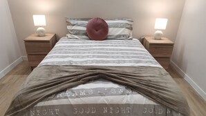 A neatly made bed with a striped blanket, two bedside lamps, and a pink pillow. - 1 bedroom apartment São Gião 10 in Tomar (Tomar)
