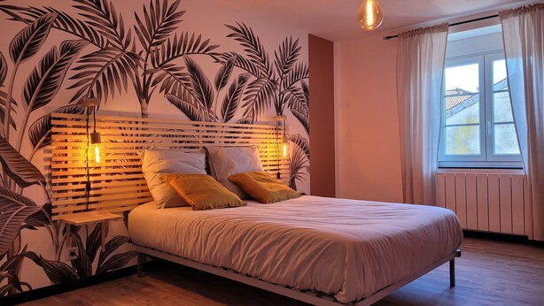 Un dormitorio con cama, cabecera iluminada, ventana con cortinas y un diseño de planta en la pared.