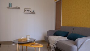 Una sala de estar moderna con un sofá gris, una mesa redonda y una silla de madera.