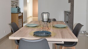 Un comedor moderno con una mesa de madera, sillas negras y una lámpara colgante original.