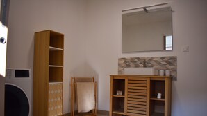 Un baño pequeño con un gabinete de madera, un perchero, un espejo y una lavadora.