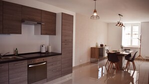 Una cocina moderna con armarios de madera, un lavavajillas de acero inoxidable y un comedor con mesa y sillas.