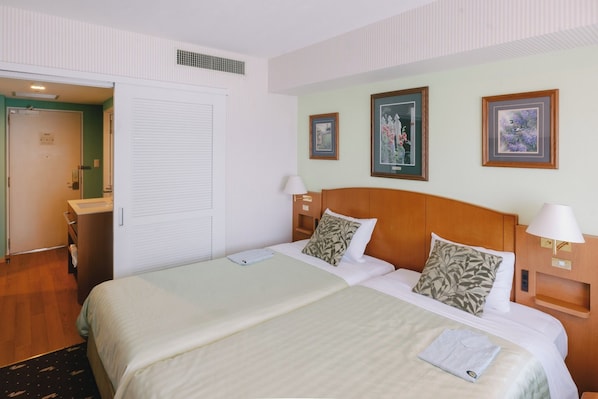 A hotel room with a large bed, two bedside tables with lamps, a wooden headboard, and framed artwork on the walls. - Standard Twin North Wing No Smoking Great Simp / Kusatsu Shiga (Kusatsu)