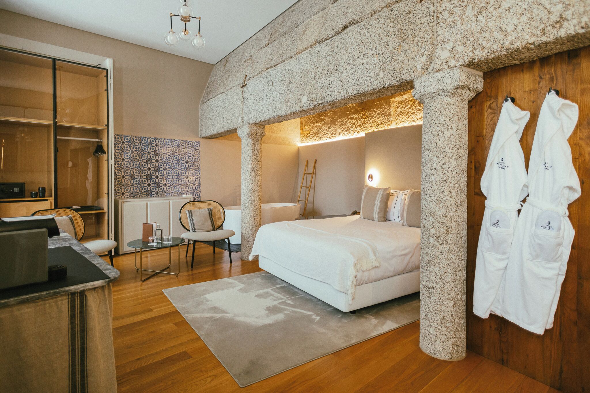 A modern bedroom with a large bed, a desk, a chair, and a wardrobe.