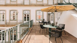 A terrace with a table and chairs, a large umbrella, and a staircase leading to an upper floor. - Torel Royal Court (Guimarães)