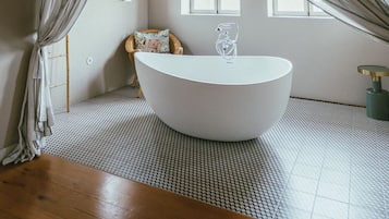 A room with a large bathtub, wooden ceiling beams, and a checkered floor.