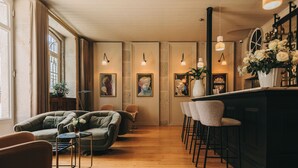 A cozy room with a wooden floor, a sofa, a small table, and a bar area with stools. - Torel Royal Court (Guimarães)