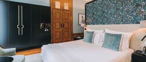 A bedroom with a large bed, a wardrobe, a desk, and a wall with a floral pattern.