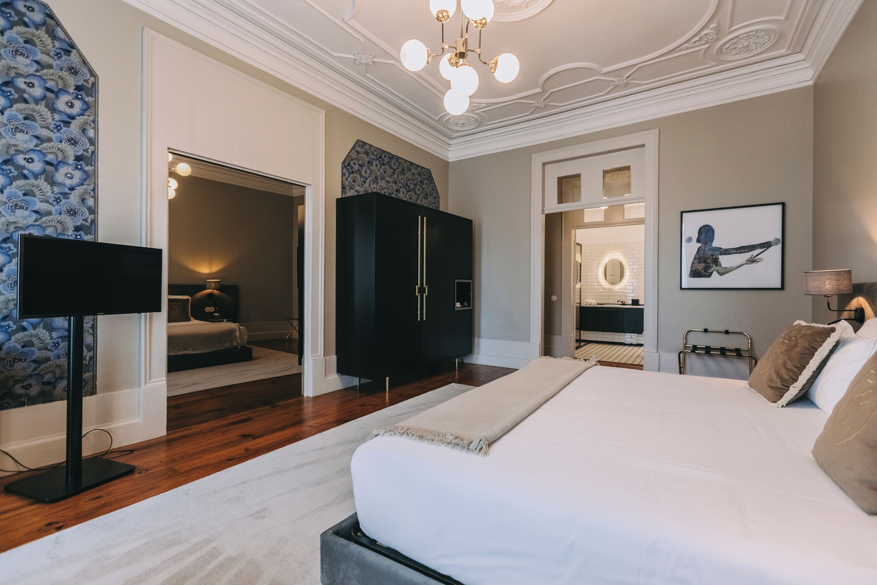 Amplia habitación con una cama grande, un armario, televisión y un baño visible a través de una puerta abierta.