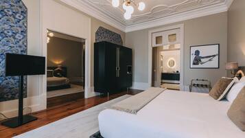 Amplia habitación con una cama grande, un armario, televisión y un baño visible a través de una puerta abierta.