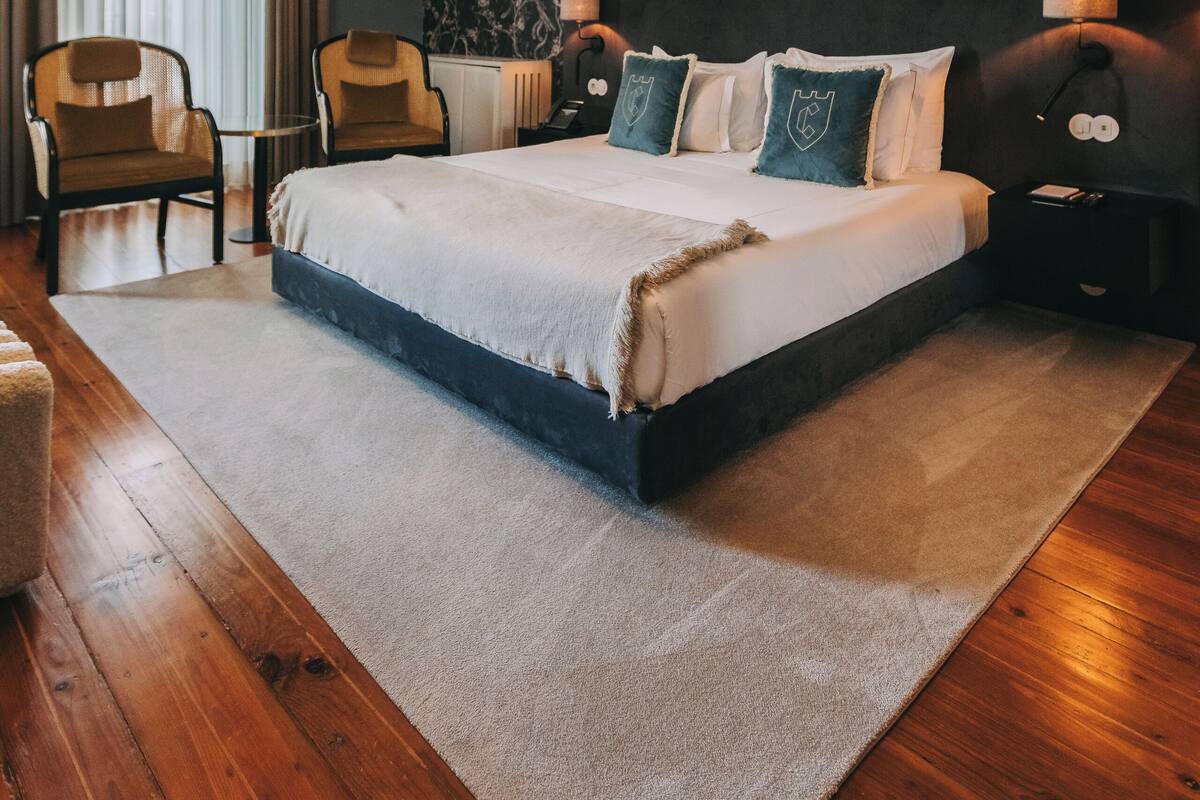 A bedroom with a large bed, two chairs, a small table, and a decorative ceiling light.