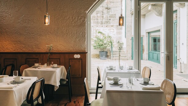A restaurant with tables set for dining, a view of the street outside, and hanging light fixtures. - Torel Royal Court (Guimarães)
