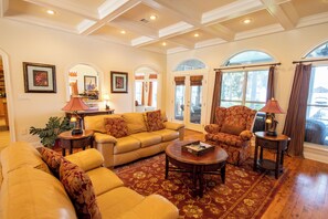 A well-lit living room with a sofa set, armchairs, a coffee table, and a patterned rug.