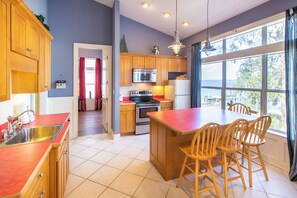 A modern kitchen with wooden cabinets, stainless steel appliances, and a large island with bar stools.