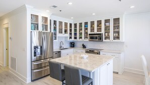 Una cucina moderna con mobili bianchi, elettrodomestici in acciaio inossidabile e un'isola in marmo.