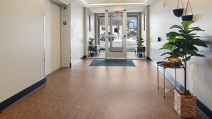 A hallway with a wooden floor, a glass door entrance, and a potted plant on a stand. -     Sip, Stay & Explore Traverse City Wine Country. Near all TC has to offer! (Traverse City)