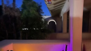 Un espace de détente extérieur accueillant, avec un canapé et une table, une plante en pot et un luminaire décoratif.