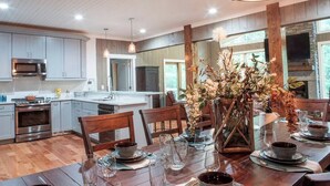 Una cocina moderna con armarios grises, una isla central y un comedor con mesa de madera para seis personas.