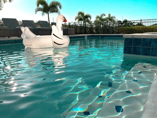 Relax by the pool with a swan-shaped float, surrounded by lounge chairs and a secure fence.