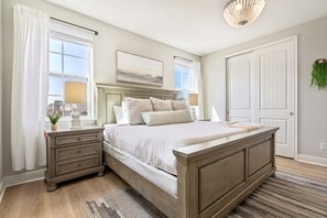 Quarto com cama, mesas de cabeceira, abajur, quadro e porta.