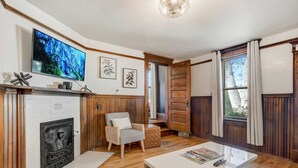 Una sala de estar acogedora con chimenea, un televisor montado en la pared y un sillón cómodo.