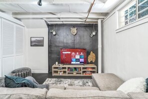 Een woonkamer met een televisie, een houten tv-meubel en een bank.