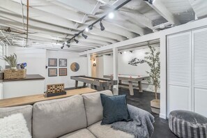Een modern interieur met een bank, een pooltafel en een tafeltennistafel.
