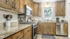 A kitchen with wooden cabinets, a stainless steel dishwasher, and a granite countertop. - 4BR Mountain Getaway w/Hot Tub Firepit & Game Room (Cascade-Chipita Park)