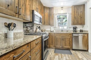 A kitchen with wooden cabinets, a stainless steel dishwasher, and a granite countertop.