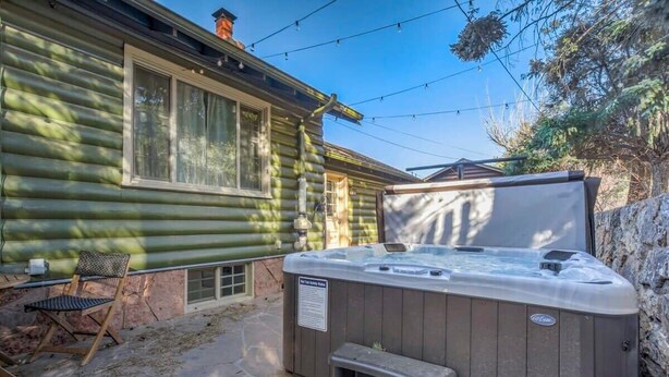 A log cabin with a hot tub, outdoor seating, and a stone wall. - 4BR Mountain Getaway w/Hot Tub Firepit & Game Room (Cascade-Chipita Park)