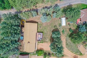 An aerial view of a property with a large house, a fenced yard, and surrounding trees.